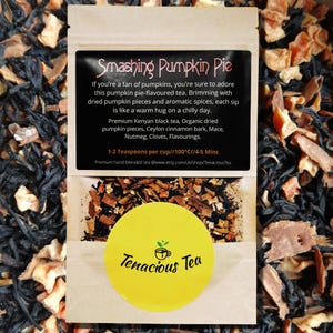 Op de afbeelding: Een verpakking "Smashing Pumpkin Pie" thee. Het etiket bevat tekst die de ingrediënten beschrijft: Keniaanse zwarte thee, pompoenstukjes, kaneel en kruiden. Een gele sticker met de merknaam "Tenacious Tea" is ook zichtbaar.