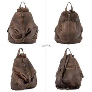 May include: A dark brown leather backpack featuring a teardrop shape, a central vertical zip, and side zip compartments. The bag includes a top handle, adjustable shoulder straps, and antique brass-toned metal hardware throughout the design.
