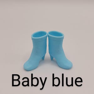 Puede incluir: Un par de botas azul beb&eacute; con tacones peque&ntilde;os. Las botas son de color liso y tienen una textura suave. El texto "Baby blue" se muestra debajo.