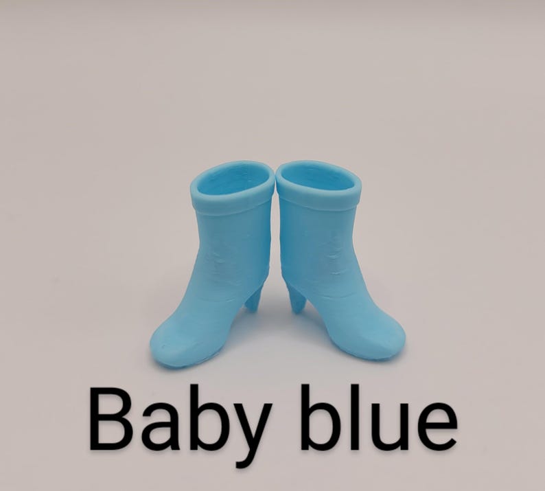 Puede incluir: Un par de botas azul beb&eacute; con tacones peque&ntilde;os. Las botas son de color liso y tienen una textura suave. El texto "Baby blue" se muestra debajo.