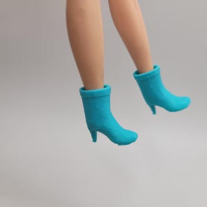 Puede incluir: Un par de botines turquesa de tac&oacute;n alto. Los botines son de color liso y tienen punta afilada y tac&oacute;n peque&ntilde;o. El fondo es de color claro.