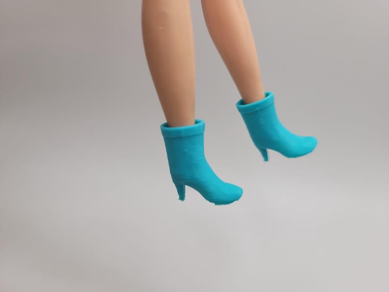 Puede incluir: Un par de botines turquesa de tac&oacute;n alto. Los botines son de color liso y tienen punta afilada y tac&oacute;n peque&ntilde;o. El fondo es de color claro.