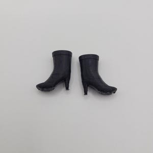 Puede incluir: Un par de botines negros con tacones de aguja. Las botas est&aacute;n hechas de un material texturizado y tienen una punta redondeada. Los tacones miden aproximadamente 5 cm de alto. Las botas est&aacute;n sobre un fondo blanco liso.