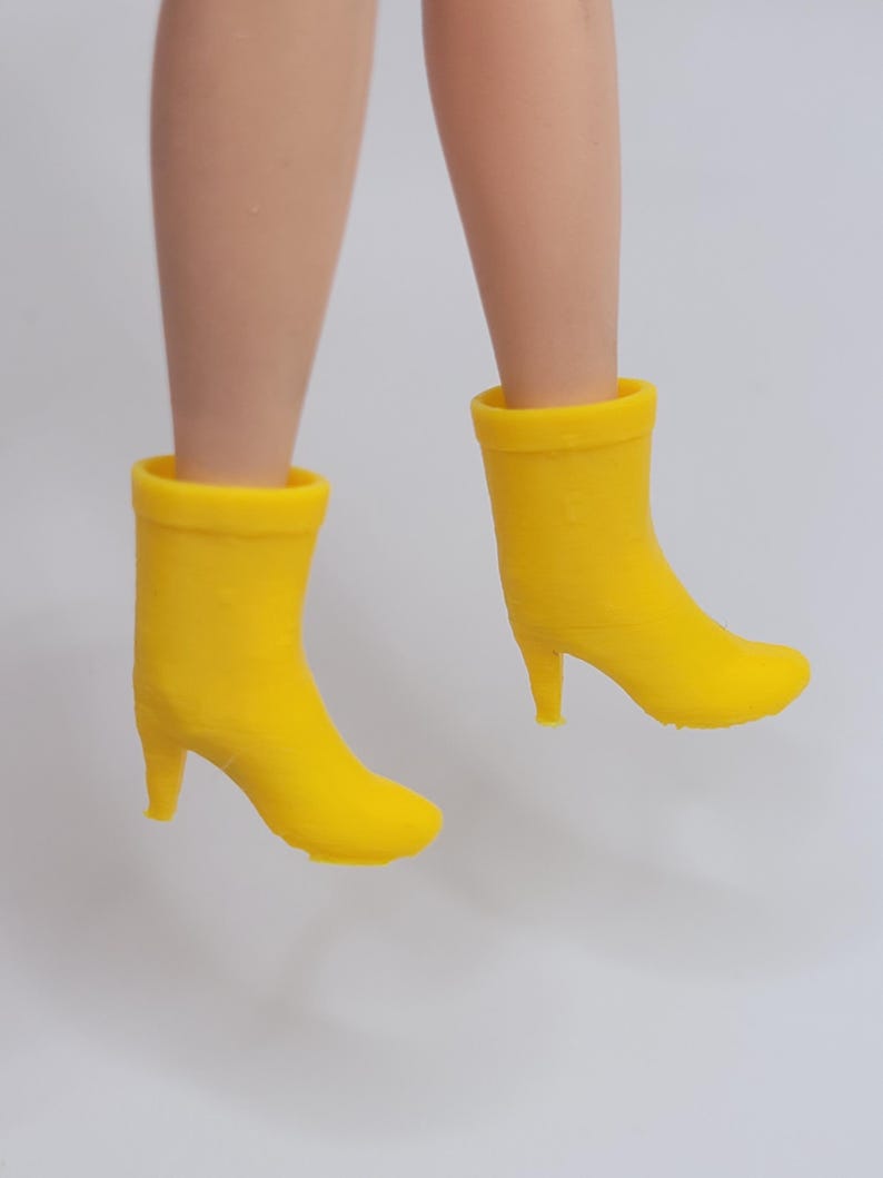 Puede incluir: Un par de botines amarillos de tac&oacute;n alto. Los botines son de color amarillo brillante y tienen un dise&ntilde;o cl&aacute;sico con punta redonda y tac&oacute;n peque&ntilde;o. Los botines se muestran suspendidos en el aire.