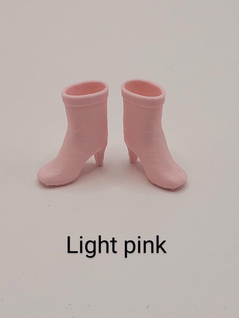Puede incluir: Un par de botines rosa claro con tacones peque&ntilde;os. Las botas est&aacute;n hechas de un material liso y tienen un dise&ntilde;o simple y cl&aacute;sico. El texto "Light pink" est&aacute; debajo.