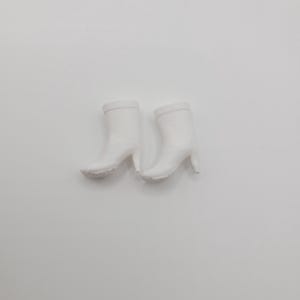 Puede incluir: Un par de botines blancos con tac&oacute;n de aguja. Las botas tienen un acabado liso y mate y una punta redondeada. Los tacones miden aproximadamente 7,6 cm de alto.
