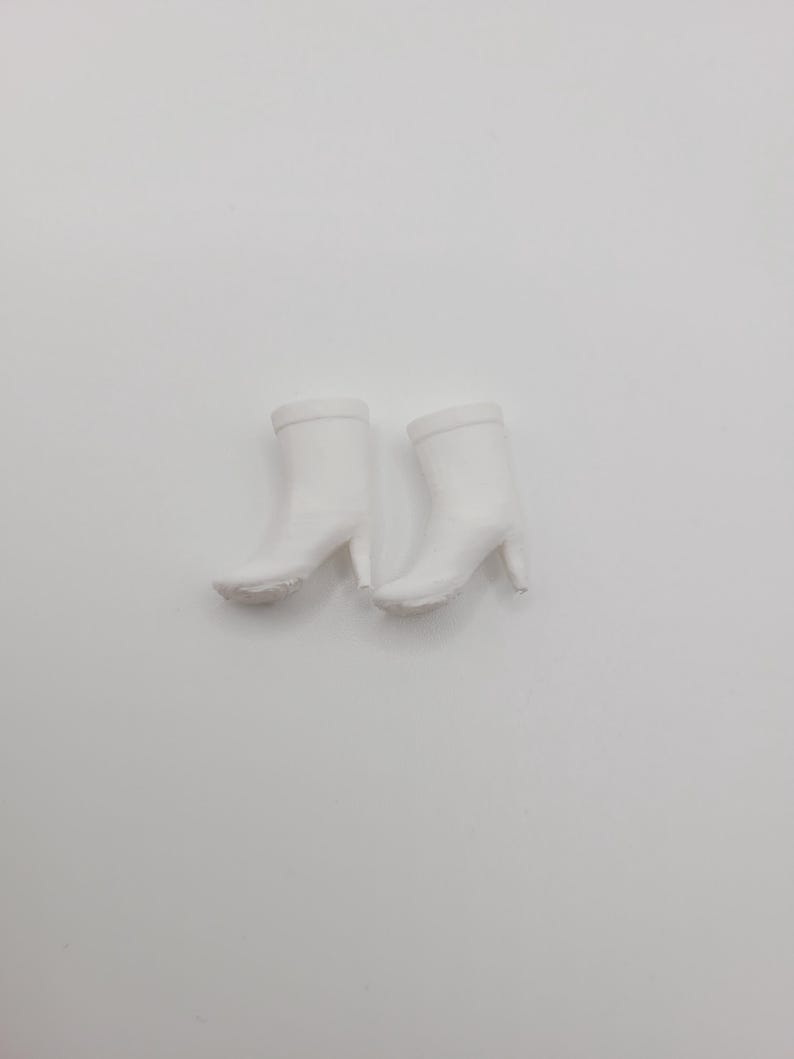 Puede incluir: Un par de botines blancos con tac&oacute;n de aguja. Las botas tienen un acabado liso y mate y una punta redondeada. Los tacones miden aproximadamente 7,6 cm de alto.