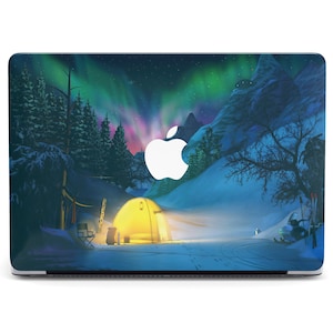 May include: A laptop skin with a design of a snowy mountain scene with a tent, trees, and a glowing aurora borealis in the sky. The Apple logo is visible on the laptop.
