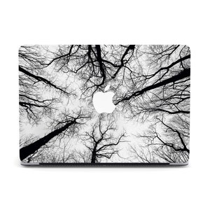 Puede incluir: Piel para portátil en blanco y negro con una silueta de ramas de árboles desnudas sobre un fondo de cielo nublado. El logotipo de Apple es visible en el portátil.