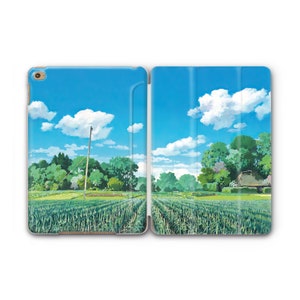 Puede incluir: Una funda para iPad azul y verde con una escena de paisaje de un campo con un cielo azul y nubes blancas. El campo es verde y tiene una pequeña casa en la distancia.