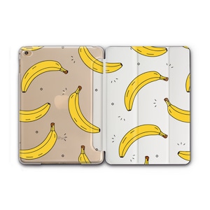 May include: A white and gold iPad case with a pattern of yellow bananas. The case is designed to protect the iPad from scratches and bumps.