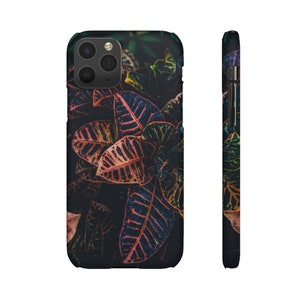 May include: A phone case with a colorful floral design. The case features a close-up of red, orange, and yellow leaves with dark green and black accents.