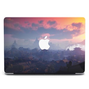 May include: A laptop with a scenic landscape design. The image features a sunset with shades of pink, orange, and blue over a detailed cityscape. A white Apple logo is centered on the laptop's cover.