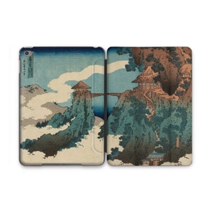 May include: A Japanese woodblock print depicting a mountain landscape with a bridge connecting two peaks. The print features a blue sky, white clouds, and green trees. There are two small buildings on the peaks, one with a thatched roof and the other with a wooden roof.