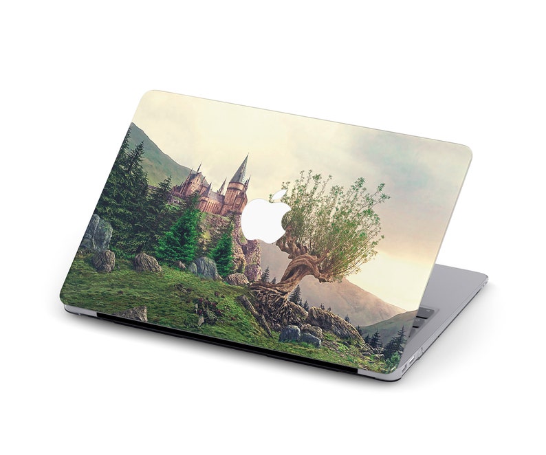 May include: A laptop skin with a whimsical design featuring a castle nestled in a mountain landscape with a large willow tree growing out of the cliffside. The tree's branches reach towards the castle, creating a magical and enchanting scene.