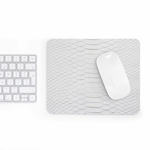May include: White computer mouse on a white snakeskin-patterned mousepad. The mousepad is on a white surface.