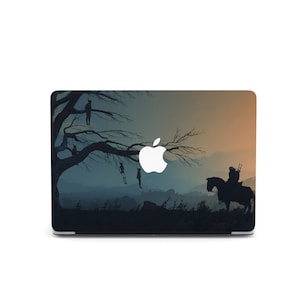 May include: A laptop skin with a dark silhouette of a tree with figures hanging from its branches and a figure on horseback in the distance. The Apple logo is visible in the center of the image.
