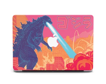 May include: A pink and orange laptop skin with a Godzilla illustration and the Japanese text "ゴジラ" (Godzilla). The illustration shows Godzilla in a city with a blue beam of light shooting from its mouth.