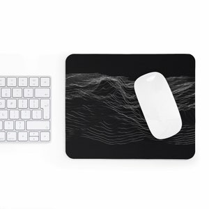 May include: A black mouse pad with a white computer mouse on top of it. The mouse pad has a design of white lines that create a wavy pattern.