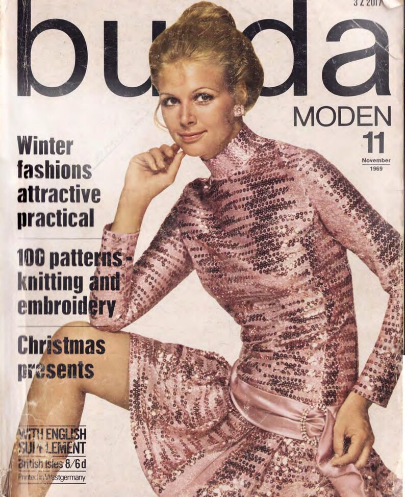 Puede incluir: Una portada de revista con una mujer que lleva un vestido de lentejuelas rosa. La revista se titula "Buda Moden" y el n&uacute;mero de la revista es 11. El texto de la portada dice "Winter fashions attractive practical 100 patterns knitting and embroidery Christmas presents".
