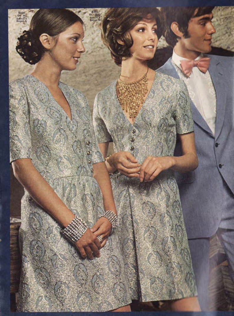 Puede incluir: Dos mujeres con vestidos a juego de color plateado y azul con estampado y mangas cortas. La mujer de la izquierda lleva una pulsera plateada. La mujer de la derecha lleva un collar dorado. Un hombre con un traje azul claro, camisa blanca y pajarita rosa claro se encuentra detr&aacute;s de las mujeres.