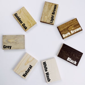 May include: A collection of small, rectangular wooden blocks, each stained a different color. Colors include Golden Oak, Light Brown, Dark Brown, Black, White Wash, Natural, and Grey. The color names are printed in black on each block.