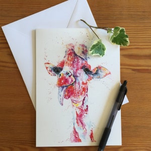May include: Watercolor painting of a giraffe with its tongue sticking out. The giraffe is painted in shades of pink, red, and blue. The background is white with splatters of paint.