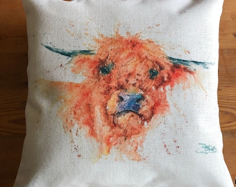 May include: A watercolor painting of a Highland cow with a light brown and orange coat. The cow is looking directly at the viewer with a curious expression. The painting is on a white linen background with a few splashes of color.