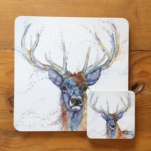 May include: A watercolour painting of a stag with large antlers. The stag is painted in shades of blue, brown, and yellow. The background is white with a subtle splatter effect.
