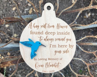 May include: Wooden ornament with a blue hummingbird cutout and the text "A hug sent from Heaven found deep inside to always remind you I'm here by your side In Loving Memory of Oscar Blanchet 1961-2020"