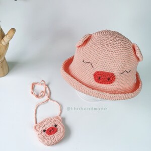 Peut inclure: Un chapeau de cochon en crochet rose avec un petit sac &agrave; main en crochet rose en forme de cochon. Le chapeau a une large bordure et le sac &agrave; main a une bandouli&egrave;re.