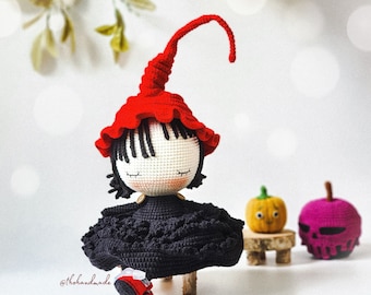 May include: A crocheted witch doll with a red hat, black dress, and red shoes. The doll is sitting on a wooden stool.