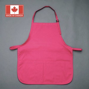 May include: A bright pink apron with two large pockets and adjustable neck straps. The apron is made in Canada.