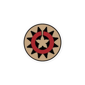 Pode incluir: Um adesivo circular de cor bege e preto com uma estrela vermelha e um círculo vermelho no centro. O círculo tem um contorno preto e é rodeado por um padrão geométrico preto e bege.
