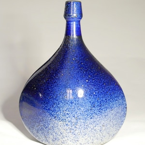 Könnte beinhalten: Eine blaue und weiße Keramikvase mit einem gesprenkelten Überzug. Die Vase hat einen breiten Boden und einen schmalen Hals.