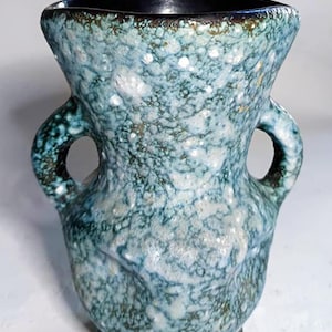 May include: A ceramic vase featuring two side handles and a wide, flared rim. The exterior is finished with a mottled glaze in shades of teal, light blue, and white, while the interior and the base are finished in a solid, dark black glaze.