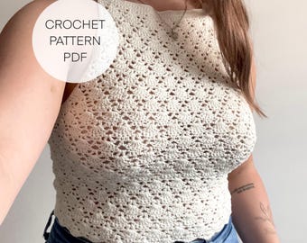 Op de afbeelding: Een wit gehaakt haltertop met een delicaat, open steekpatroon. Het topje heeft een gegolfde zoom en wordt gedragen met een blauwe jeans. "CROCHET PATTERN PDF" staat in een cirkel op de afbeelding.