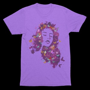 May include: Purple t-shirt with a graphic of a woman's face surrounded by colorful butterflies. The butterflies are in a watercolor style and the woman's face is stylized.