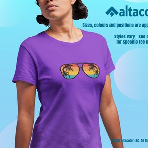 Może przedstawiać: Fioletowy T-shirt z grafiką okular&oacute;w przeciwsłonecznych odbijających palmy i zach&oacute;d słońca. Tekst "Styles vary - see our site for specific tee model." jest nadrukowany pod grafiką.