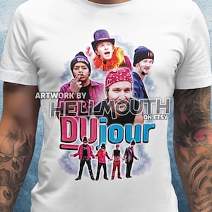 May include: White t-shirt featuring a graphic of a band with the text "DUJOUR" in pink and blue. The artwork includes the text "ARTWORK BY HELLMOUTH ON ETSY". The design showcases a group of people in various outfits, with a retro aesthetic.