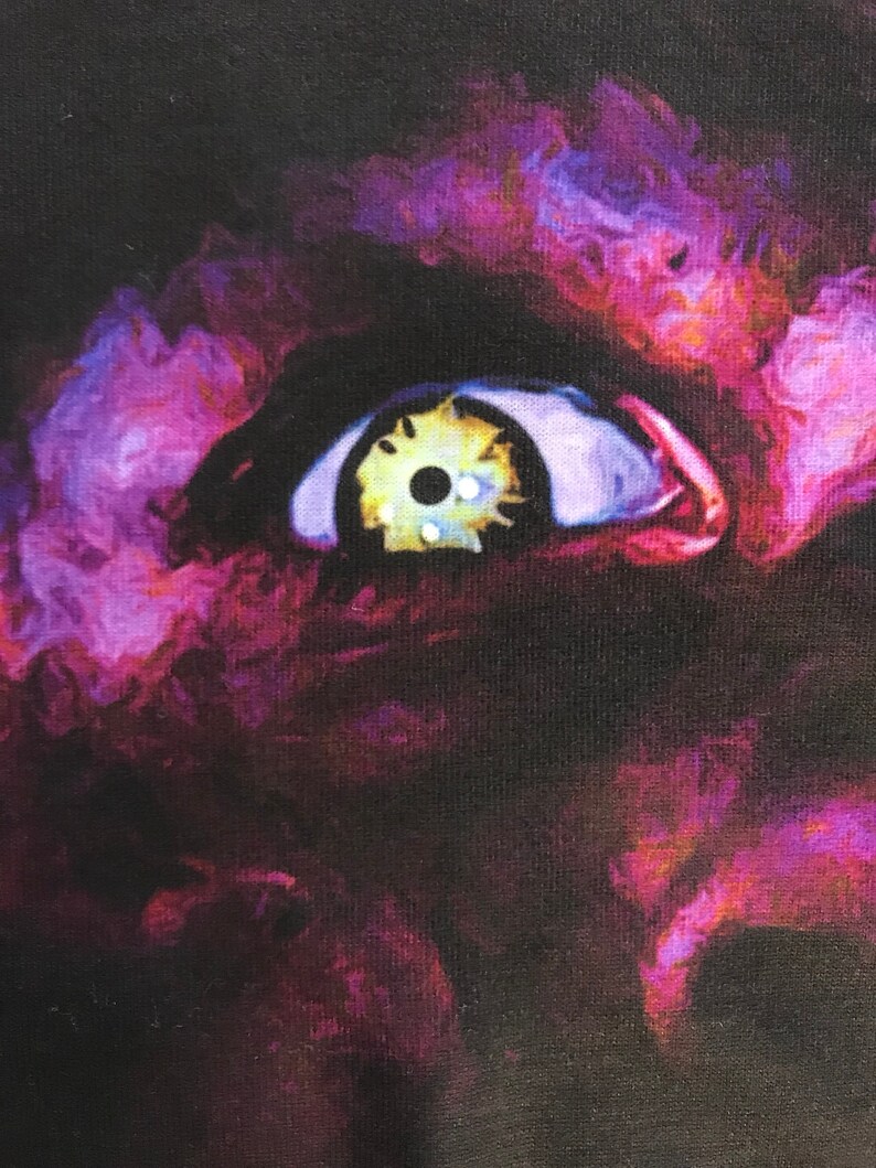 May include: A close-up of a purple and yellow eye with a black pupil. The eye is surrounded by a dark purple and black background.