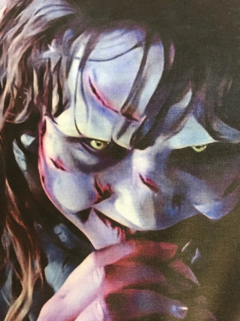 May include: A close-up of a creepy, pale-faced character with dark hair and piercing green eyes. The character has a sinister smile and appears to be wearing a dark shirt.