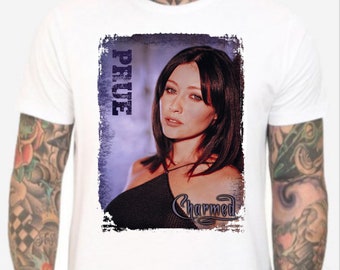 Puede incluir: Camiseta blanca con una imagen desgastada de una mujer con el pelo largo y oscuro. La imagen tiene el texto "PRUE" y "Charmed".