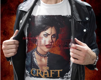 Könnte beinhalten: Weißes T-Shirt mit einem Grafikdruck einer Frau aus dem Film "The Craft". Die Grafik ist im Used-Look gehalten, der Titel "The Craft" ist in goldenen Buchstaben.