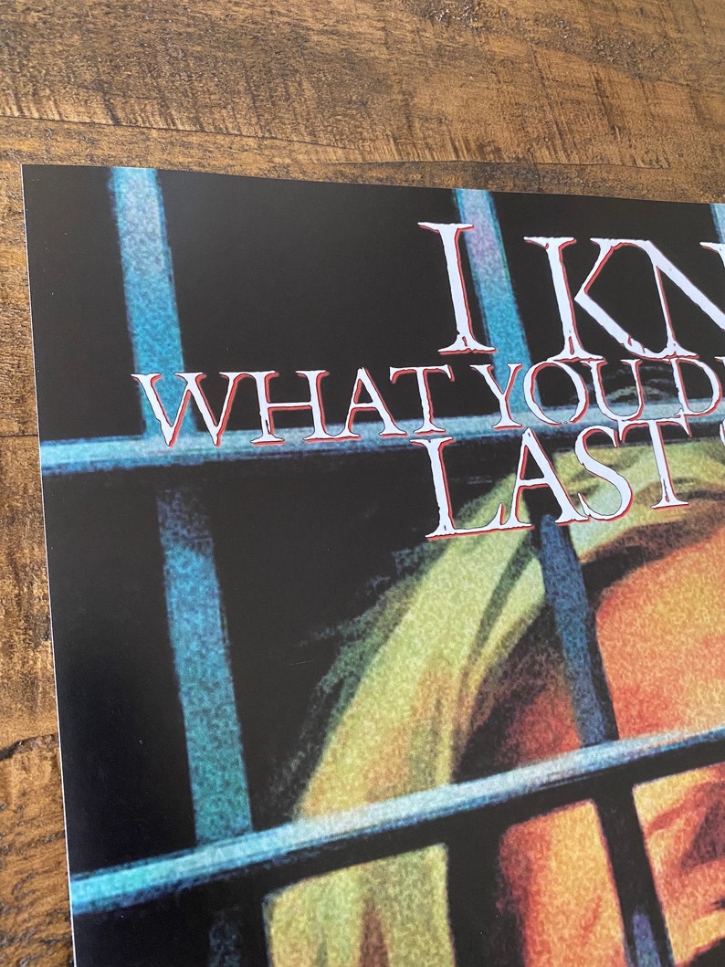 May include: A black and white poster with the text "I Know What You Did Last Summer" in white letters. The poster features a close-up of a person's face behind prison bars.