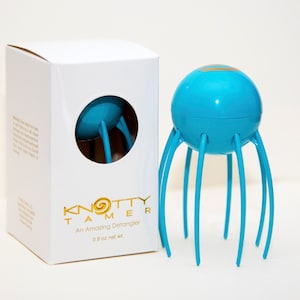 May include: A turquoise Knotty Tamer hair detangler with a spherical head and six curved legs, next to its white box. The box has a circular cutout showing the product inside. The box reads "Knotty Tamer An Amazing Detangler 0.8 oz net wt."