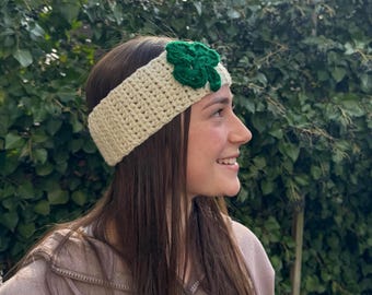 May include: A white crocheted headband with a green shamrock design. The headband is worn by a person with long brown hair.