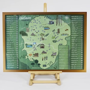 May include: A framed map of Dartmoor, featuring a green and brown color scheme. The map includes illustrations of landmarks, roads, and place names. The map is displayed on a wooden easel.