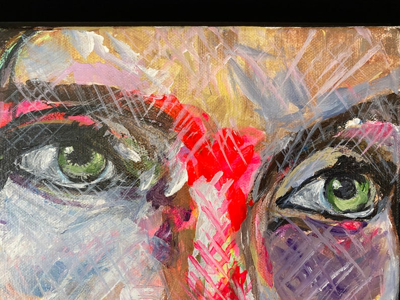 May include: Abstract painting of a face with two green eyes, red, pink, white, and black paint strokes. The background is a light brown color.