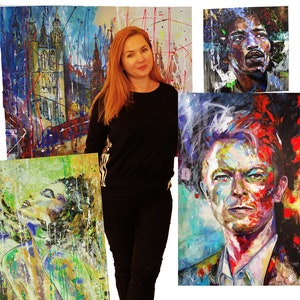 May include: A woman stands in front of four colorful paintings. The paintings are abstract and feature a variety of colors and textures. The woman is wearing a black shirt and jeans.